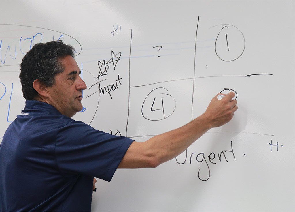 precollege-faq-1 an image of a teacher writing on a white board in a classroom setting